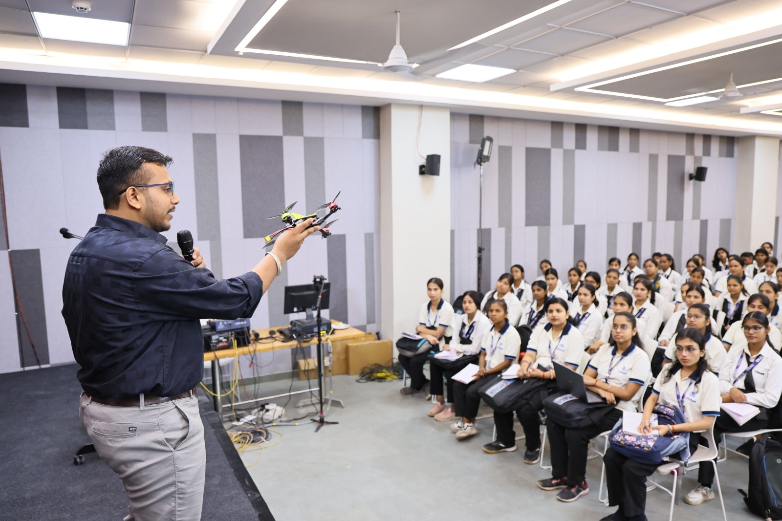 An instructor presents a drone to students during a workshop